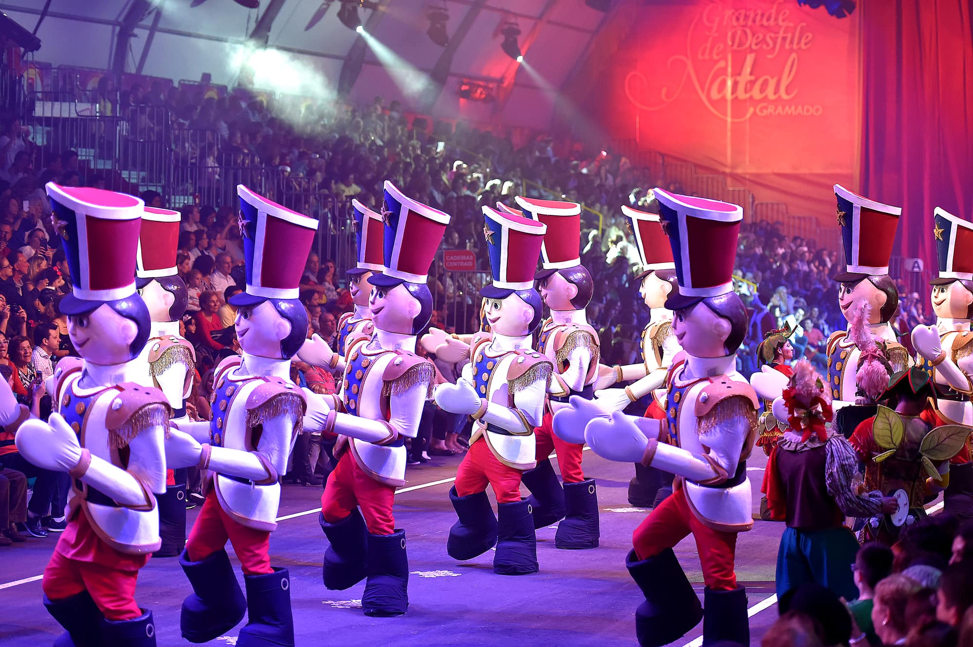 Tropa de soldadinhos de chumbo desfilando diante da plateia no Grande Desfile de Natal