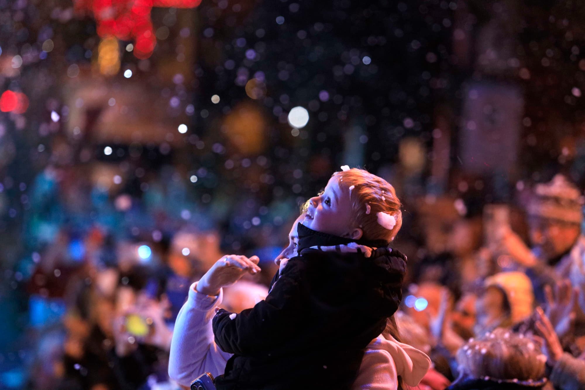Criança no colo do pai vendo a primeira neve cair no Natal Luz de Gramado